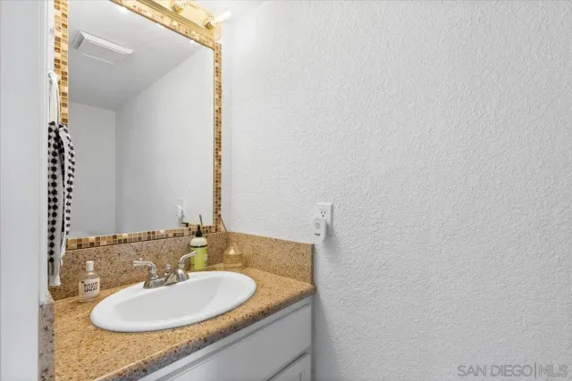 a bathroom with a granite countertop sink and a mirror