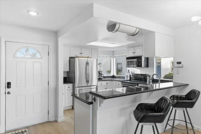 a kitchen with stainless steel appliances granite countertop a sink refrigerator and cabinets