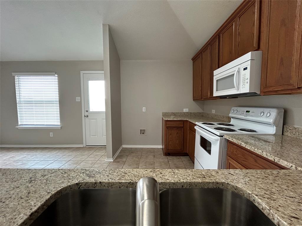 1249 Round Pen Run Fort Worth, TX 76052 - Photo 5 of 28 a kitchen with granite countertop a sink stove and cabinets
