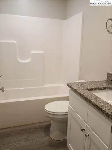a bathroom with a granite countertop toilet and a bathtub