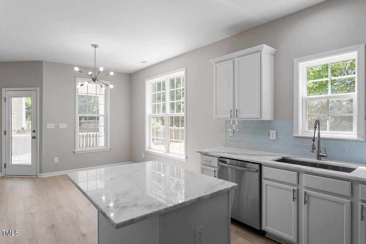 617 McCarthy Drive Clayton, NC 27527 - Photo 11 of 44 a kitchen with granite countertop a sink dishwasher and white cabinets with wooden floor