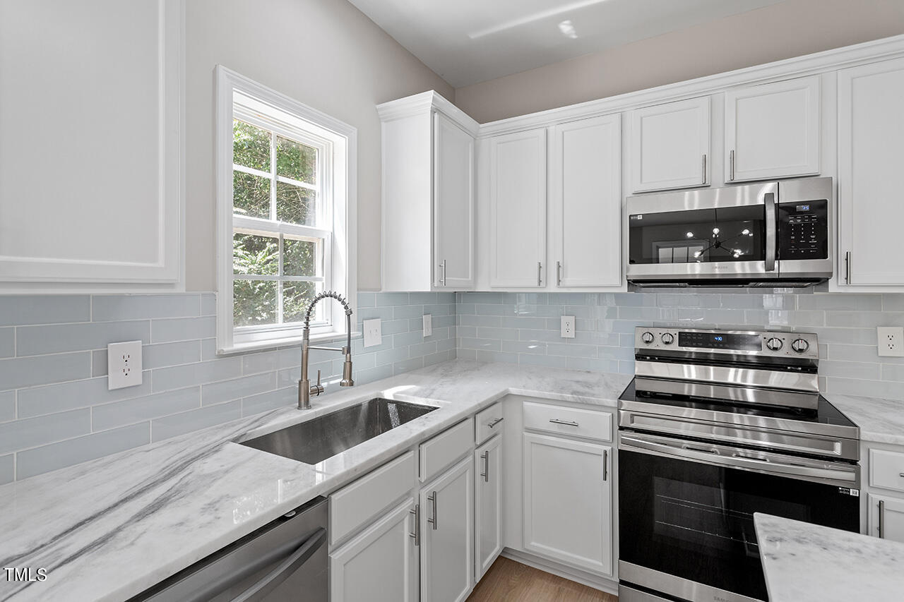 617 McCarthy Drive Clayton, NC 27527 - Photo 10 of 44 a kitchen with stainless steel appliances granite countertop a sink a stove a microwave and cabinets