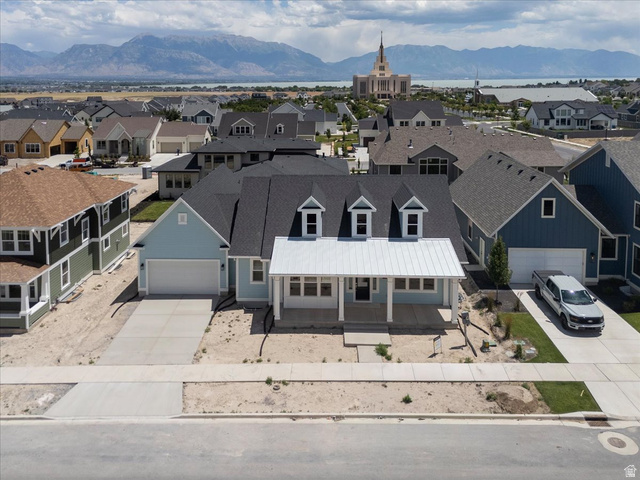 952 Mathilda Drive, Unit 156 Saratoga Springs, UT 84045 - Photo 4 of 25 Light blue siding home featuring a white metal roof over the front porch, three dormer windows, and a two-car garage