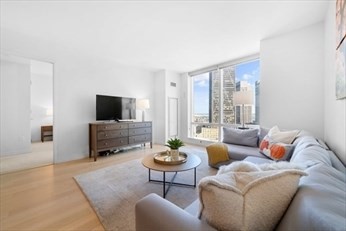 1 Franklin Street, Unit 2406 Boston, MA 02110 - Photo 4 of 22 a living room with furniture a flat screen tv and a large window