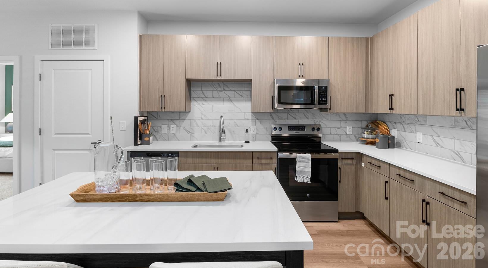 2546 Perimeter Pointe Parkway, Unit 1G Charlotte, NC 28208 - Photo 33 of 48 a kitchen with kitchen island granite countertop a sink a stove and cabinets