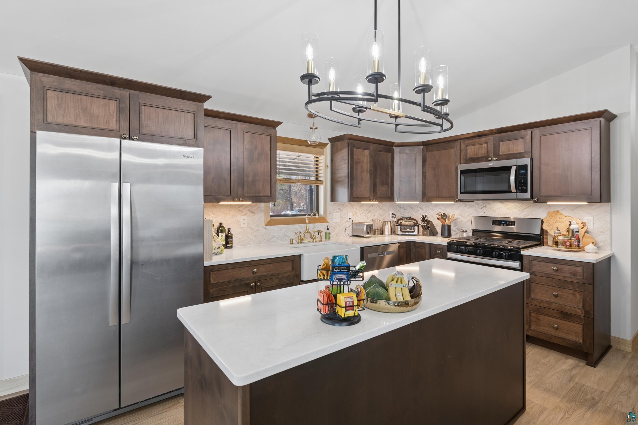 3903 Lake Park Road Ashland, WI 54806 - Photo 13 of 37 Kitchen featuring stainless steel appliances, dark wood finish cabinetry, lofted ceiling, a kitchen island, and tasteful backsplash