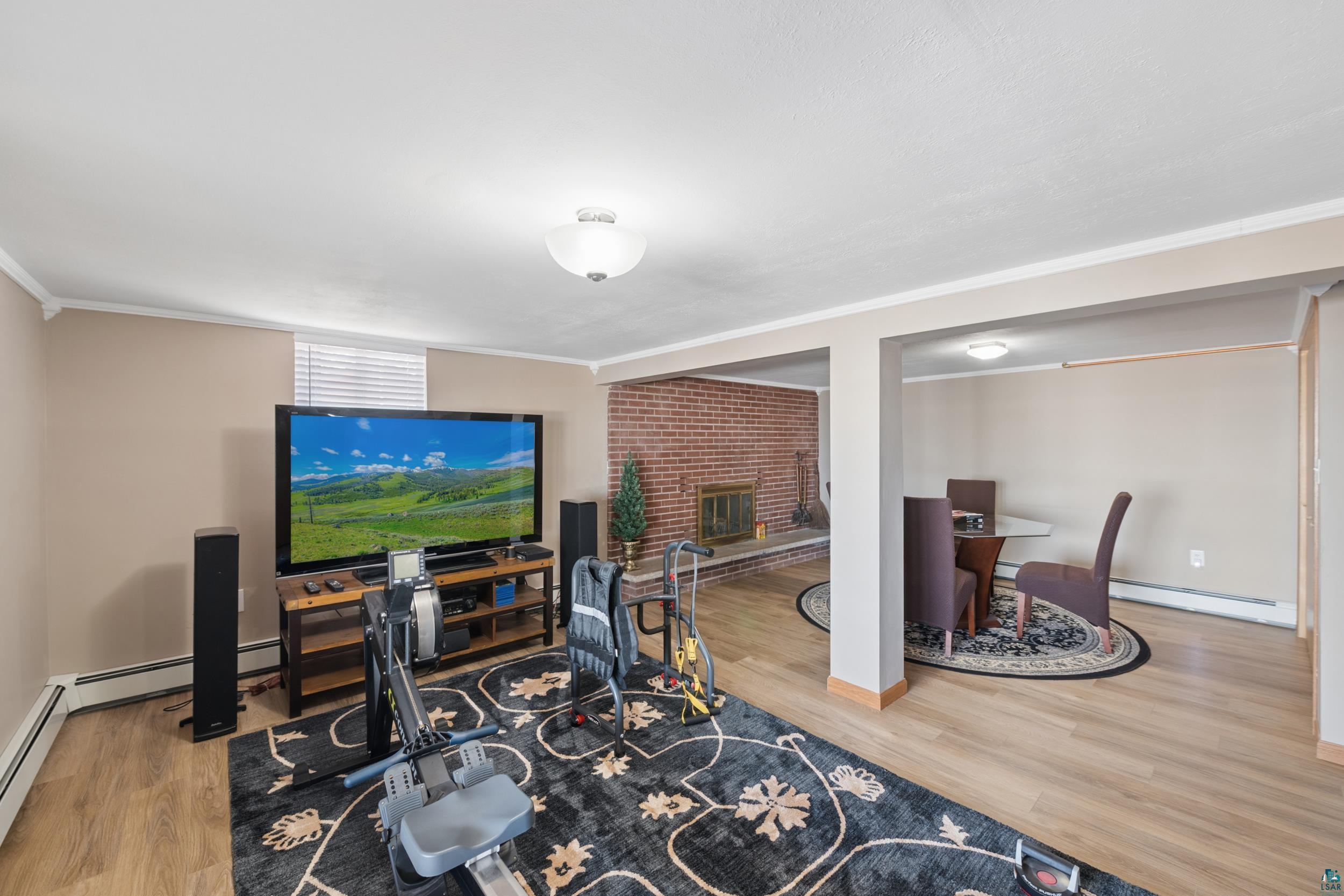 3903 Lake Park Road Ashland, WI 54806 - Photo 16 of 37 Living area with light wood-style floors, a brick fireplace, and a baseboard heating unit