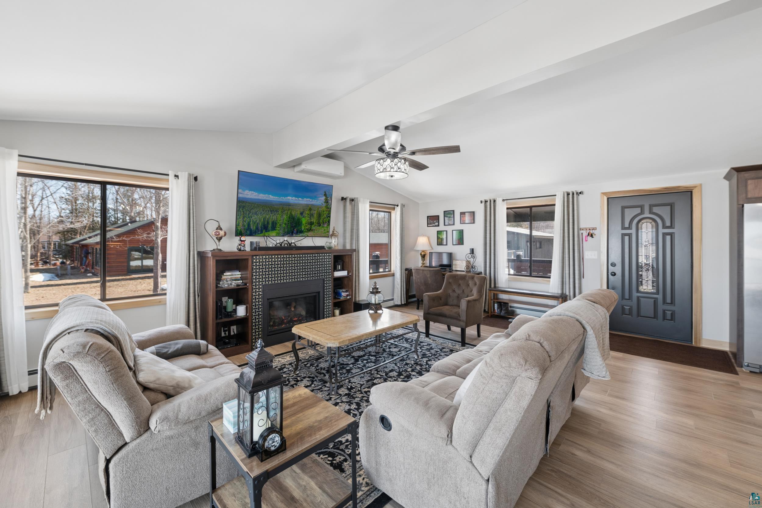 3903 Lake Park Road Ashland, WI 54806 - Photo 19 of 37 Living area featuring beam ceiling, light wood-style floors, a fireplace, ceiling fan, and healthy amount of natural light