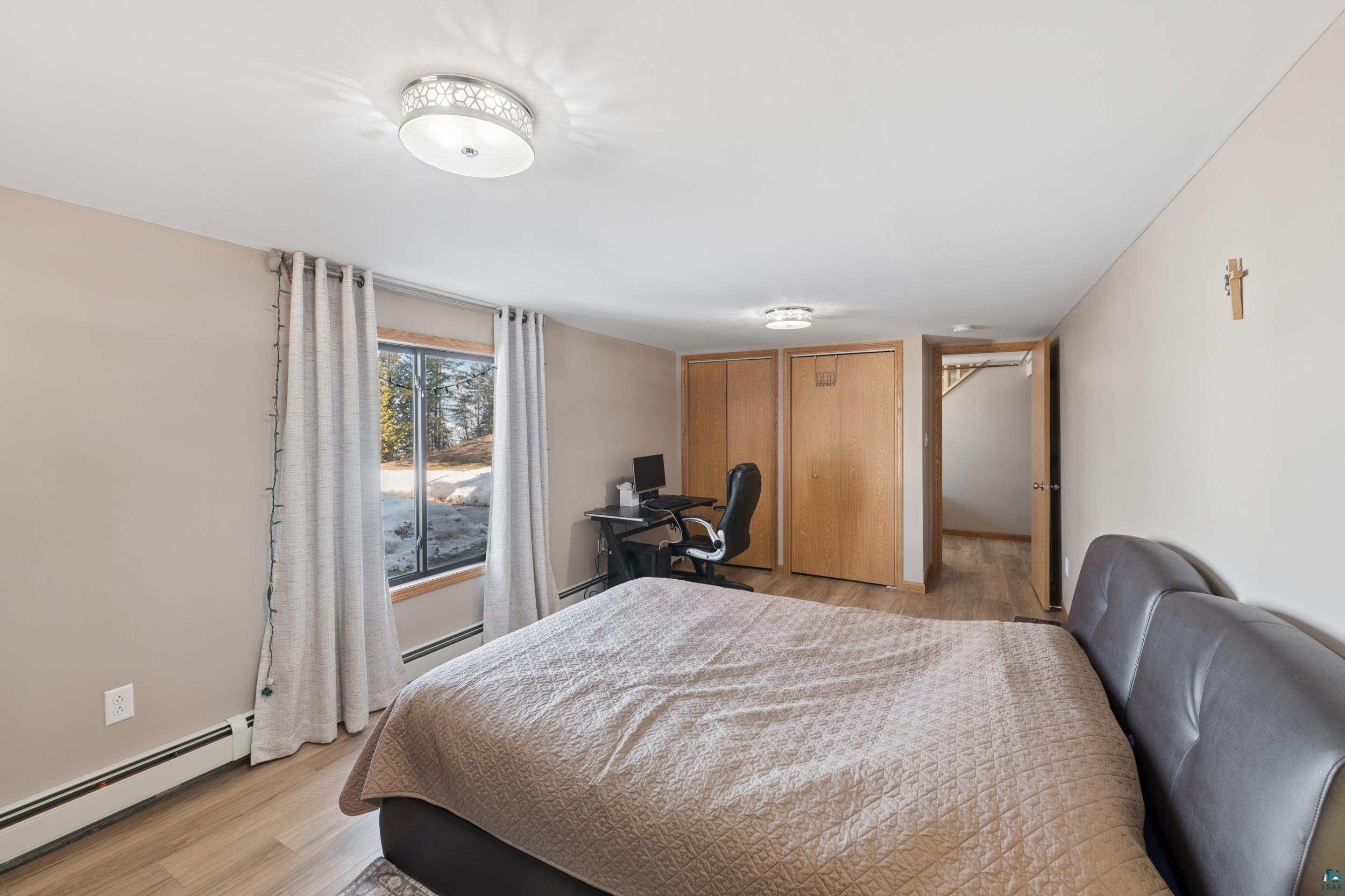 3903 Lake Park Road Ashland, WI 54806 - Photo 29 of 37 Bedroom featuring light wood-type flooring, baseboard heating, two closets, and an office area