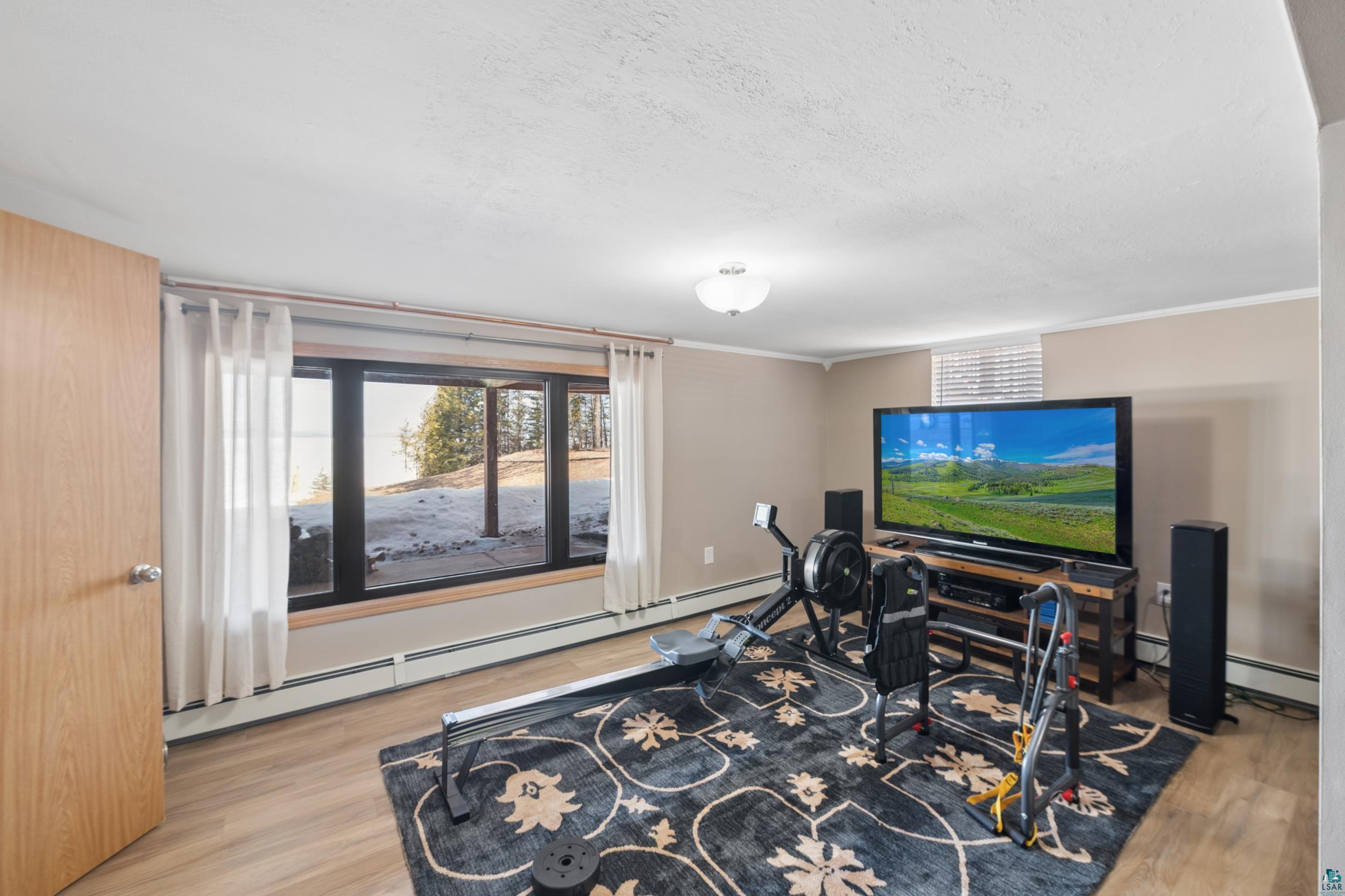 3903 Lake Park Road Ashland, WI 54806 - Photo 30 of 37 Exercise room featuring baseboard heating, light wood-style floors, a textured ceiling, and crown molding