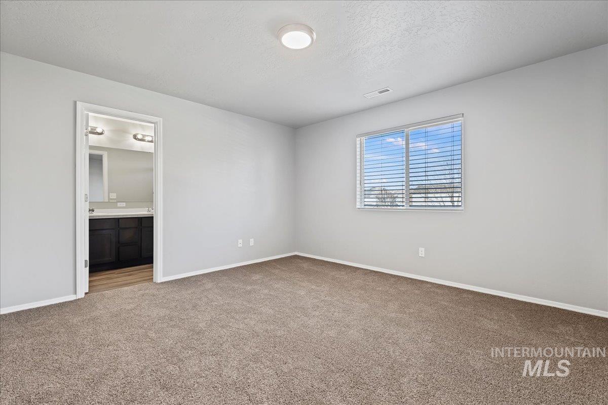 916 West Woodpine Street Meridian, ID 83646 - Photo 22 of 32 Unfurnished bedroom featuring a textured ceiling, carpet floors, and ensuite bath