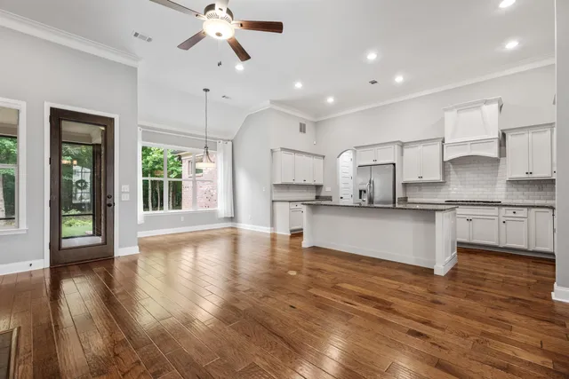 a view of an empty room with wooden floor fireplace and a window