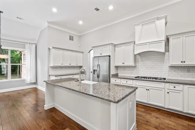 a kitchen with granite countertop a sink center island a stove cabinets and living room view