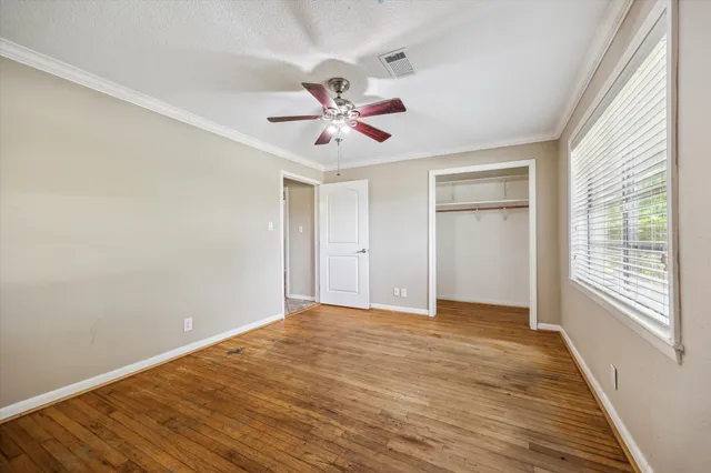 a view of empty room with wooden floor and fan