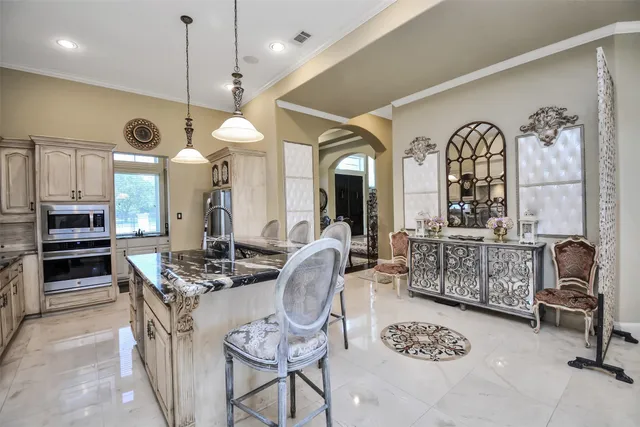 a kitchen with stainless steel appliances granite countertop a stove a sink dishwasher a dining table and chair with wooden floor