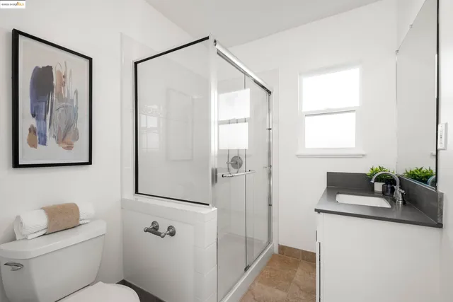 a bathroom with a granite countertop sink a mirror a toilet and shower