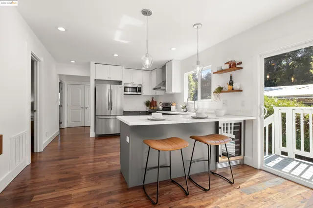 a open kitchen with stainless steel appliances granite countertop a stove a refrigerator a oven a sink with island chairs and wooden floor