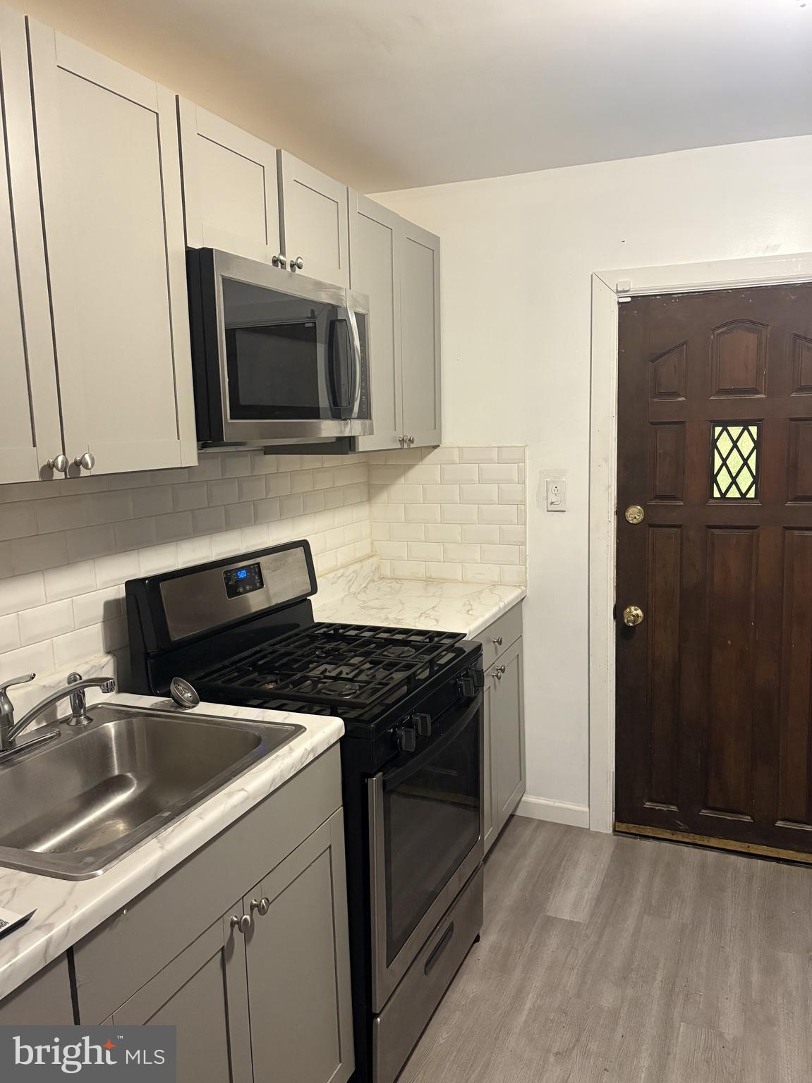 6380 Marsden Street Philadelphia, PA 19135 - Photo 2 of 9 a kitchen with stainless steel appliances a stove a microwave and a sink