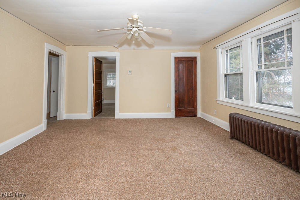 3114 Neosho Road Youngstown, OH 44511 - Photo 14 of 25 Unfurnished room with radiator, plenty of natural light, light colored carpet, and a ceiling fan