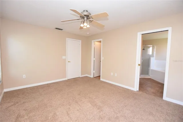 an empty room with closet and a chandelier fan