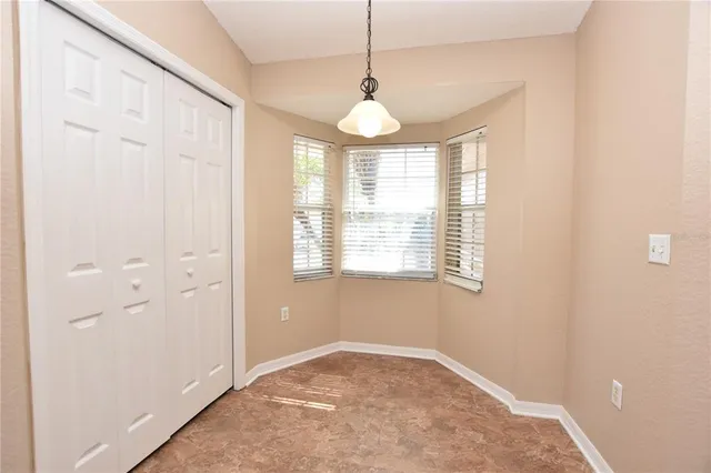 a view of an empty room with window and chandelier fan