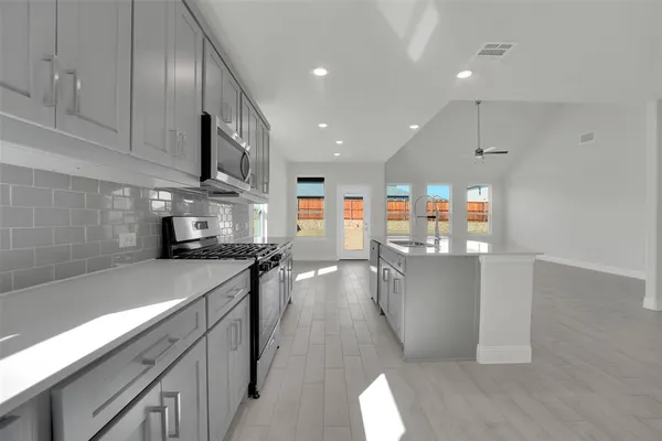 a kitchen with stainless steel appliances a sink a stove top oven a counter space and cabinets