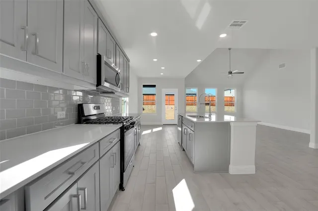 a kitchen with stainless steel appliances a sink a stove top oven a counter space and cabinets