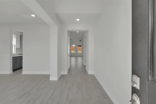a view of a hallway with wooden floor and bathroom