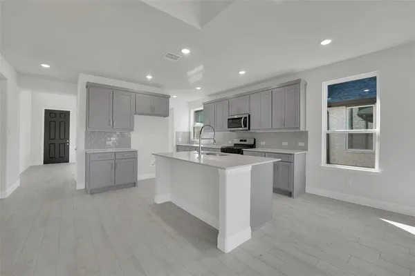 a kitchen with white cabinets and window