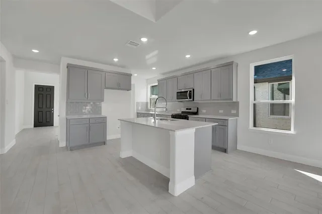 a kitchen with white cabinets and window