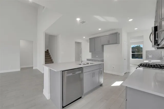 a kitchen with stainless steel appliances granite countertop a sink a stove a refrigerator and a stove