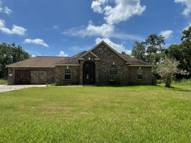 a front view of a house with a garden and trees