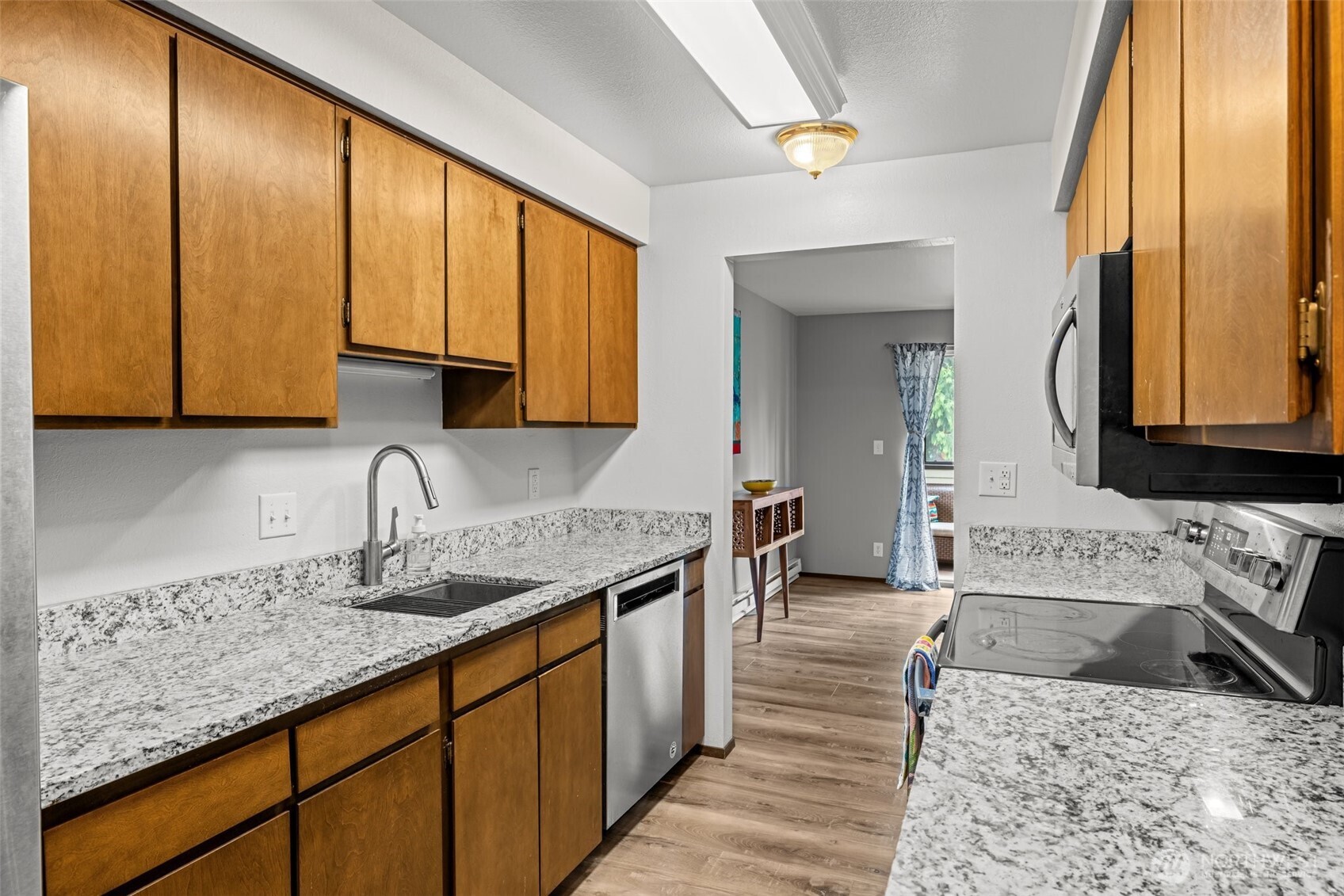 8516 196th Street Southwest, Unit 311 Edmonds, WA 98026 - Photo 11 of 28 a kitchen with stainless steel appliances granite countertop sink stove and cabinets