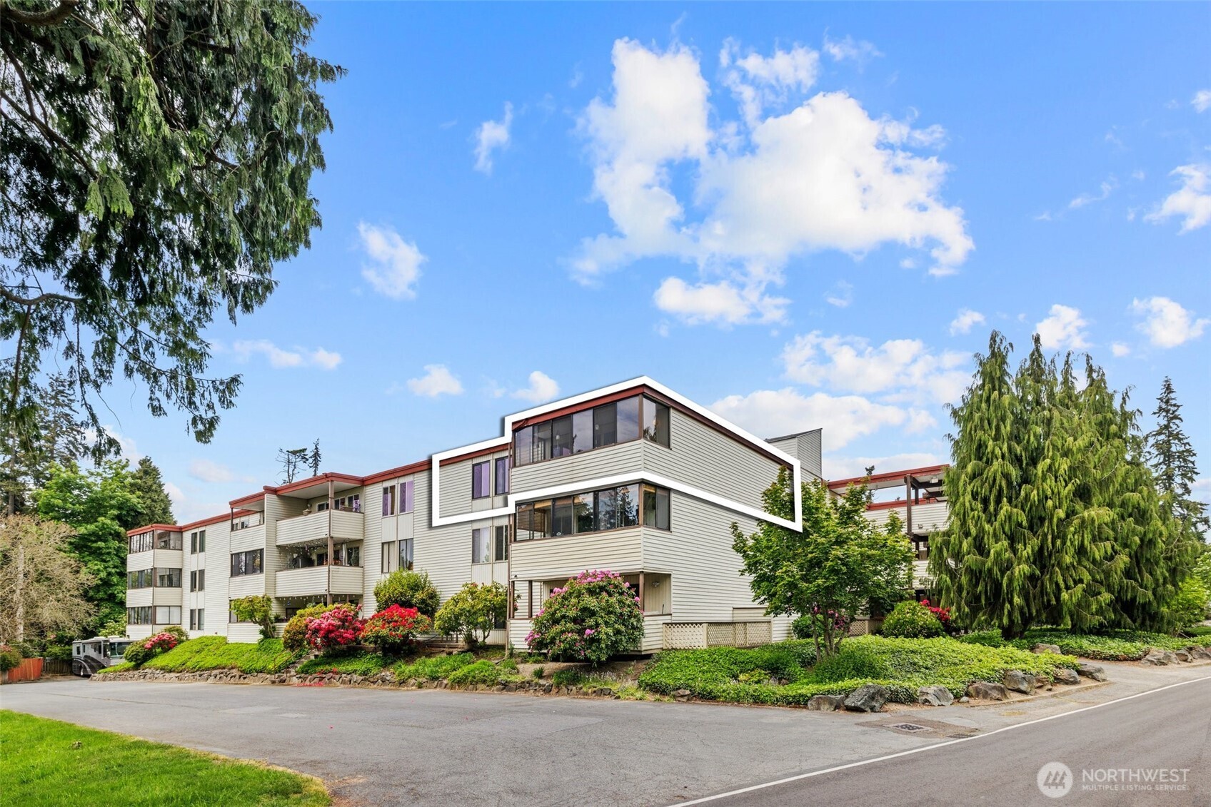 8516 196th Street Southwest, Unit 311 Edmonds, WA 98026 - Photo 2 of 28 a blue and white building with a flower garden in front of it