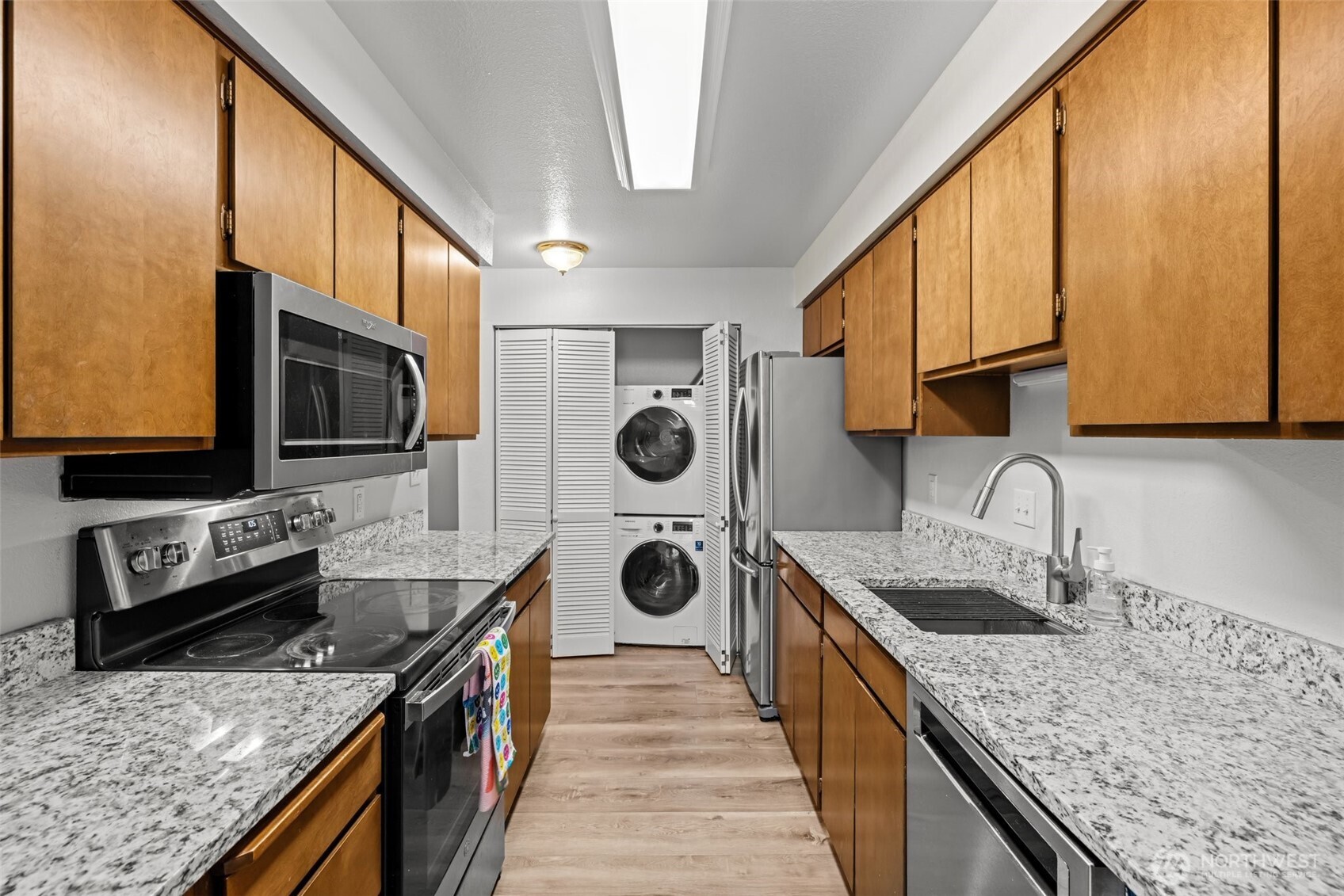 8516 196th Street Southwest, Unit 311 Edmonds, WA 98026 - Photo 10 of 28 a kitchen with stainless steel appliances granite countertop a stove a sink and a microwave