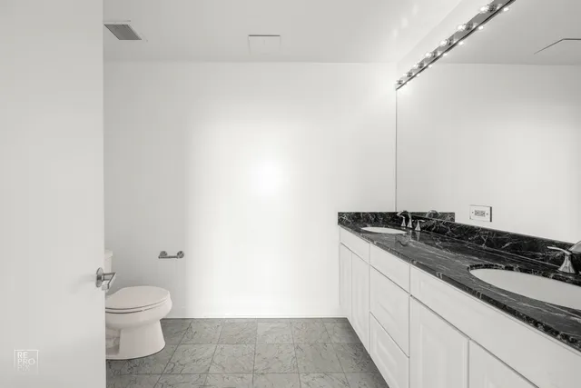 a bathroom with a granite countertop sink toilet and a mirror