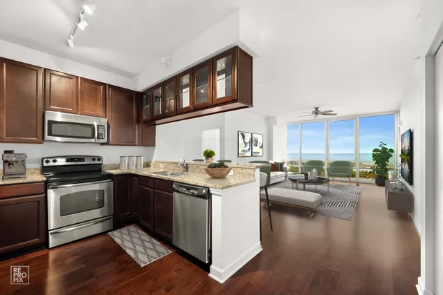 a kitchen with a stove top oven a sink dishwasher a dining table and chairs with wooden floor