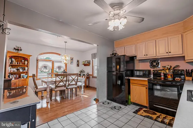 a kitchen with stainless steel appliances granite countertop a refrigerator a stove a sink a dining table and chairs with wooden floor