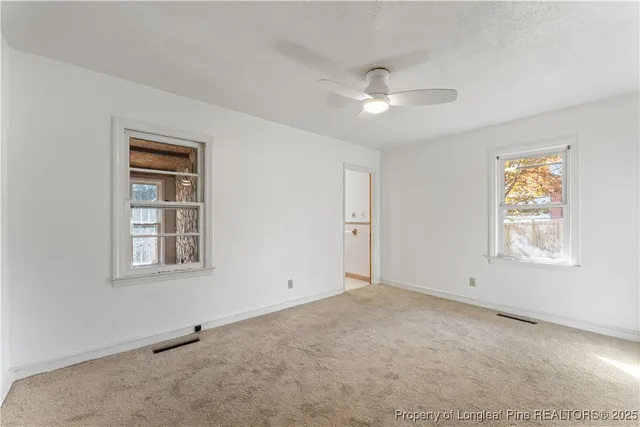 an empty room with a window and a ceiling fan