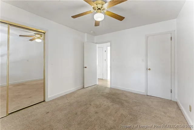an empty room with closet and a chandelier fan