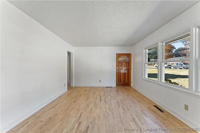 a view of an empty room with a window and wooden floor