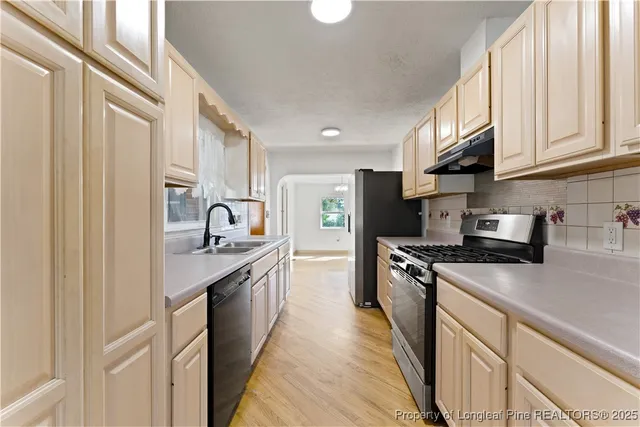 a kitchen with stainless steel appliances granite countertop a sink stove refrigerator and cabinets