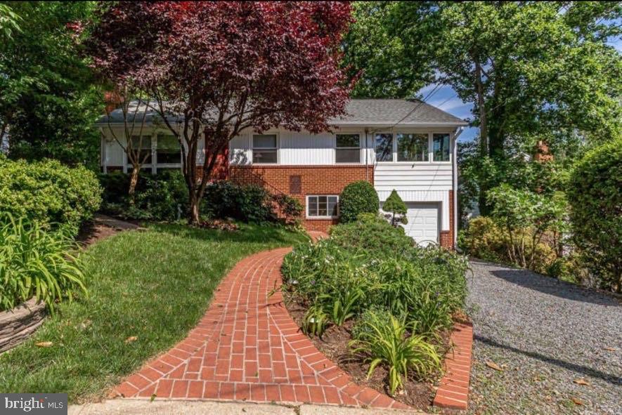 Charming home with lush landscaping and path.