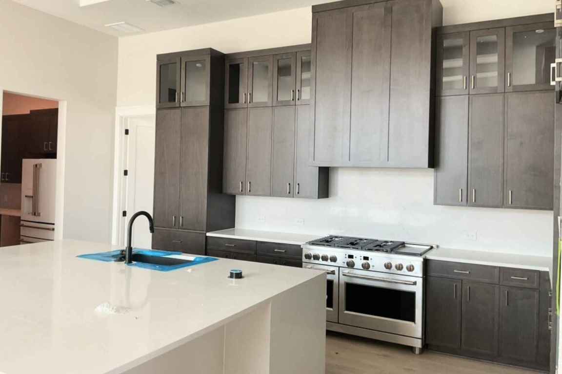 1400 Paxton Lane Georgetown, TX 78633 - Photo 4 of 39 Kitchen featuring high end appliances, glass insert cabinets, light stone countertops, light wood-style floors, and an island with sink
