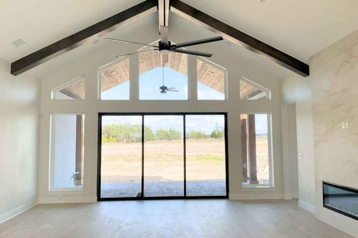 1400 Paxton Lane Georgetown, TX 78633 - Photo 6 of 39 Unfurnished living room featuring high vaulted ceiling, a high end fireplace, a ceiling fan, beamed ceiling, and concrete flooring
