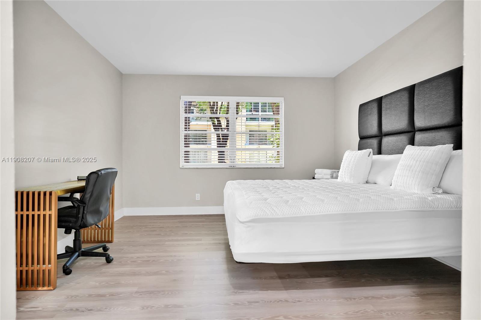 100 Ashbury Road, Unit 103 Hollywood, FL 33024 - Photo 8 of 28 a bed sitting in a bedroom next to a window