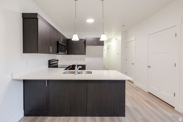 4661 Poplar Way, Unit R303 Mapleton, UT 84664 - Photo 14 of 17 Kitchen featuring dark wood finish cabinets, a peninsula, hanging light fixtures, stainless steel appliances, and light wood-type flooring