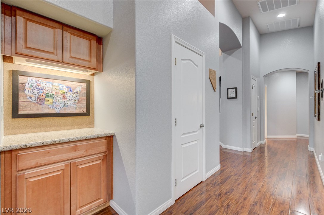 1604 Cattle Ranch Place Henderson, NV 89002 - Photo 19 of 99 Rich hardwood floors extend through a well-lit hallway with architectural arched doorways and a convenient built-in cabinet.