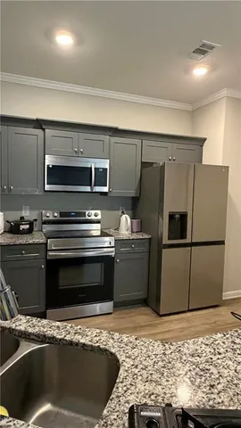 a kitchen with stainless steel appliances kitchen island granite countertop a refrigerator and a stove top oven