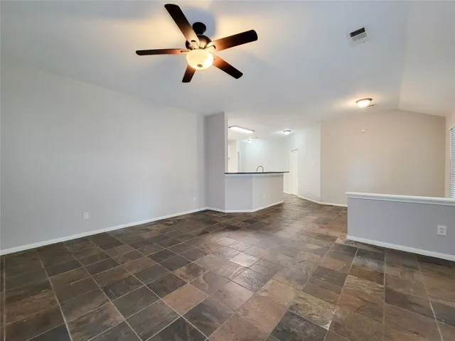 an empty room with a ceiling fan and a rug